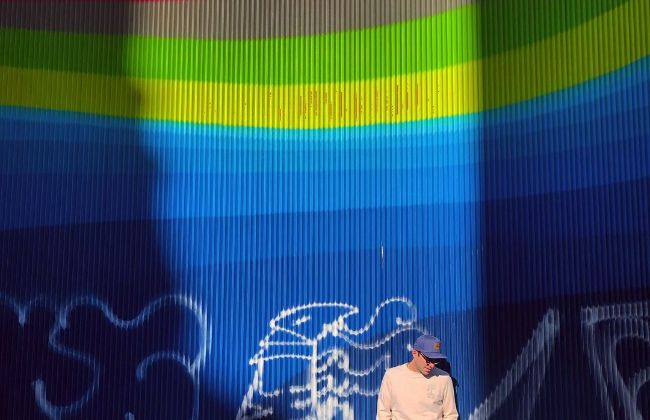 A picture of Zachary Quinto in Spain in front of a rainbow mural. 